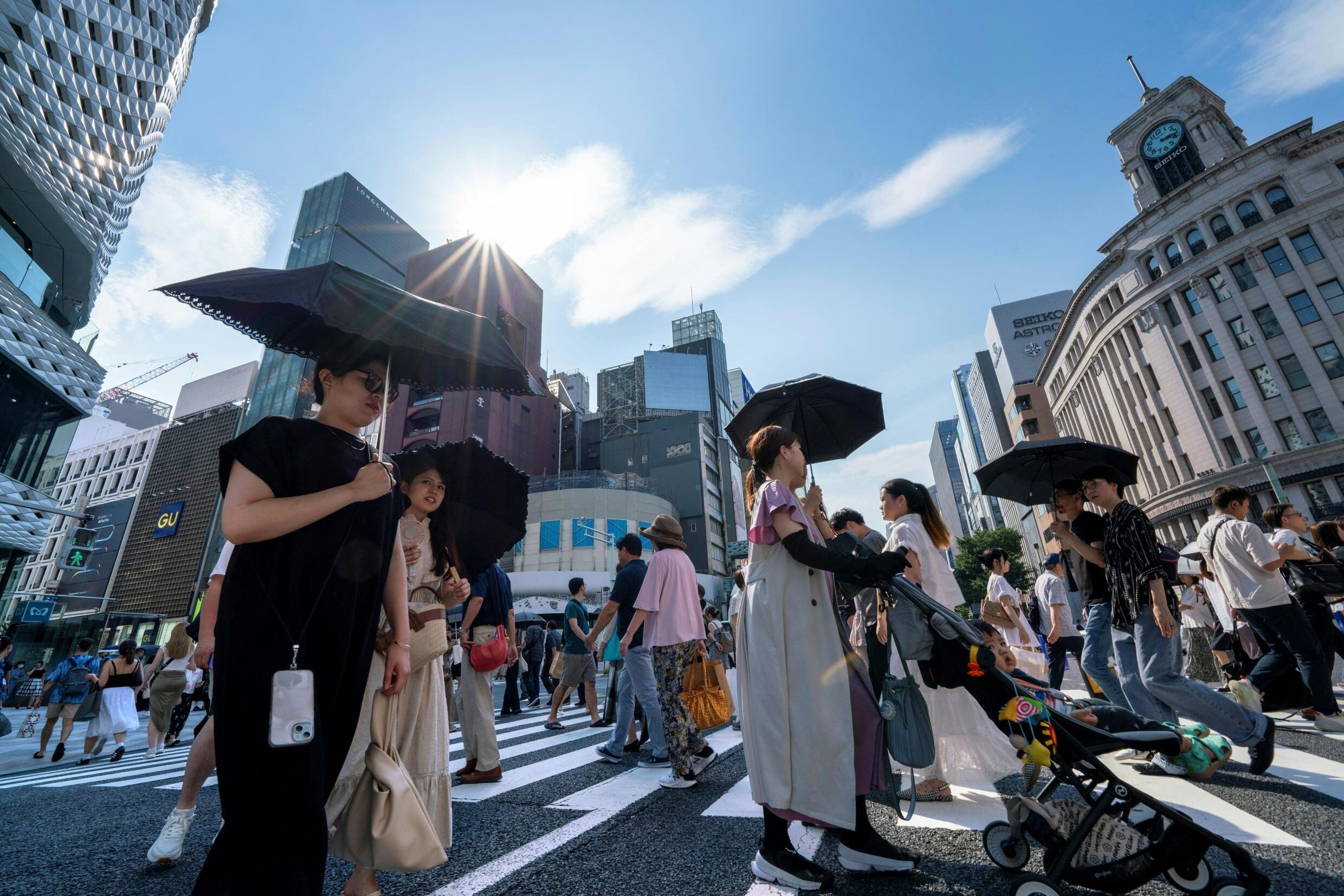 Des piétons marchent sur un passage à niveau dans le centre de Tokyo où les températures ont atteint 35 °C, le 8 juillet 2024.