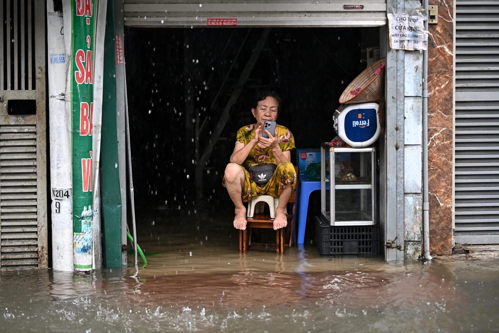 Une femme assise au-dessus des eaux de crue dans sa maison à Hanoï (Vietnam), le 11 septembre 2024.