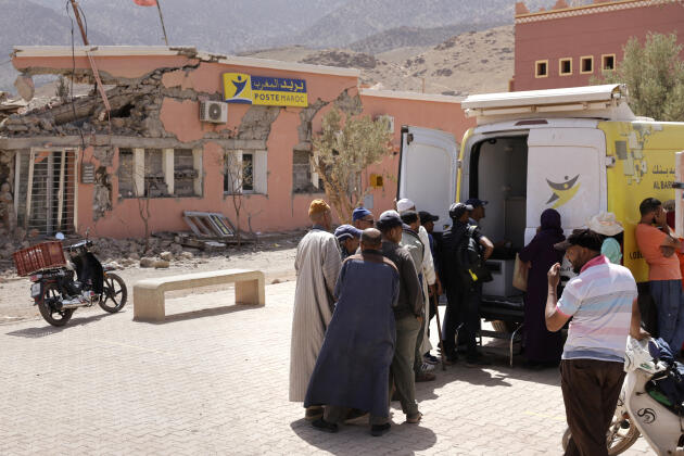 Des gens attendent devant un van faisant office de banque, devant le batiment détruit de la poste, à Talat N’Yaaquob, au Maroc, le 5 septembre 2024.