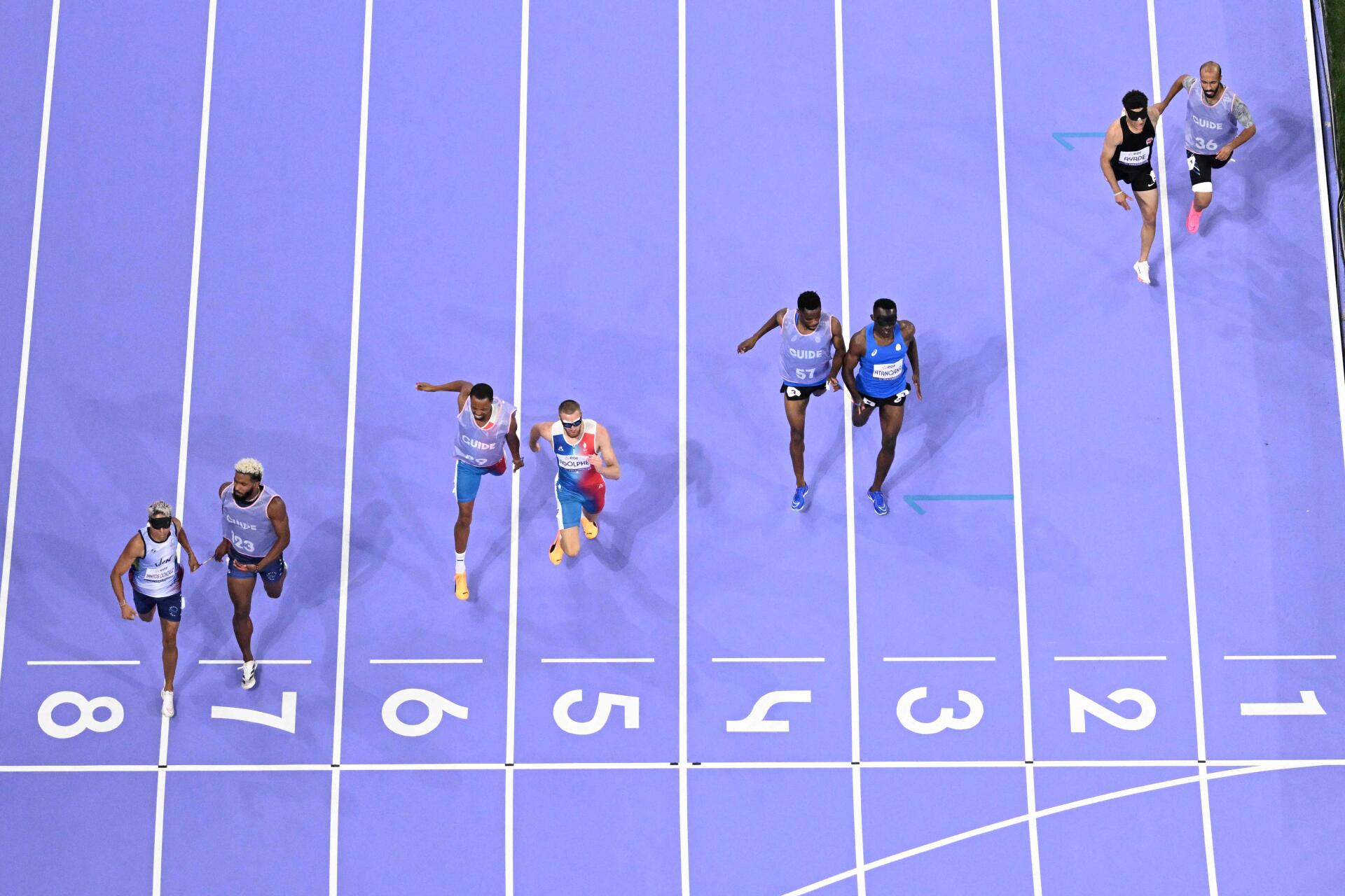 Le Vénézuélien Anderson German Santos Gonzalez et son guide Eubrig Jose Maza Caraballo, le Français Timothée Adolphe et son guide Jeffrey Lami, le guide Donard Ndim Nyamjua et le réfugié Guillaume Junior Atangana en compétition pendant la finale masculine du 400 m (T11) aux Jeux paralympiques de Paris 2024. Au Stade de France, à Saint-Denis, le 1ᵉʳ septembre 2024. Le Français a décroché la médaille d’argent.