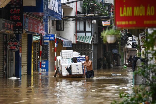 Des personnes transportent des produits de base sur un bateau à travers les eaux de crue dans une rue de Hanoï (Vietnam), le 12 septembre 2024.